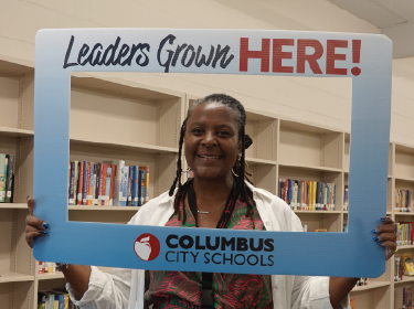 a woman holding a leaders grown here cutout picture frame